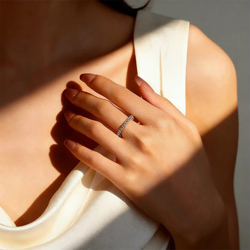 Aliança eternidade fina de moissanite no dedo à luz do sol