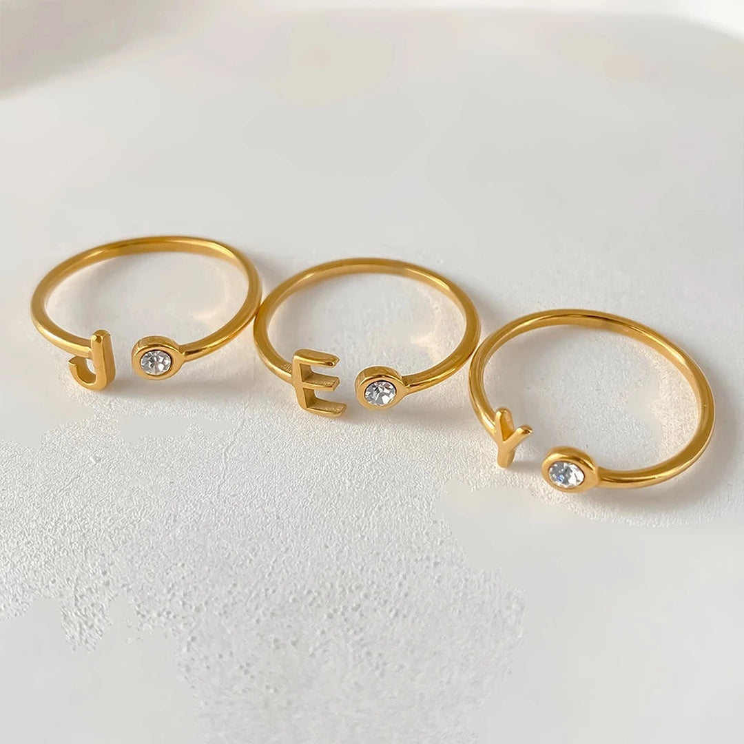 Anéis abertos com inicial J, E e Y dourados e pedra cristal