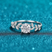 Anel de Moissanite 1ct com Folhas Cravejadas em prata 925 sobre fundo verde com brilho