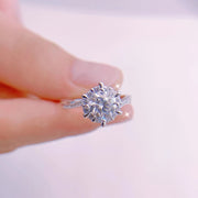 Anel de moissanite com halo floral segurado entre os dedos
