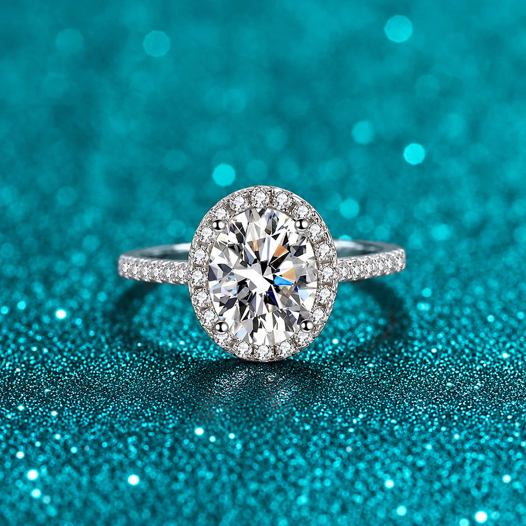 Anel Oval de Moissanite com Halo e Aro Cravejado em prata 925 sobre fundo verde com brilho