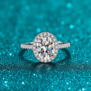 Anel Oval de Moissanite com Halo e Aro Cravejado em prata 925 sobre fundo verde com brilho