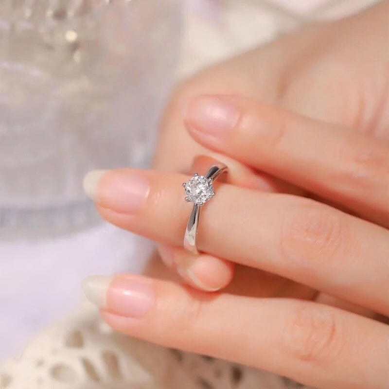 Mão feminina segurando o anel solitário de moissanite no dedo