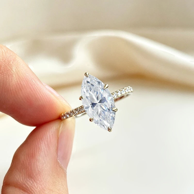 Anel de moissanite marquise dourado segurado entre os dedos