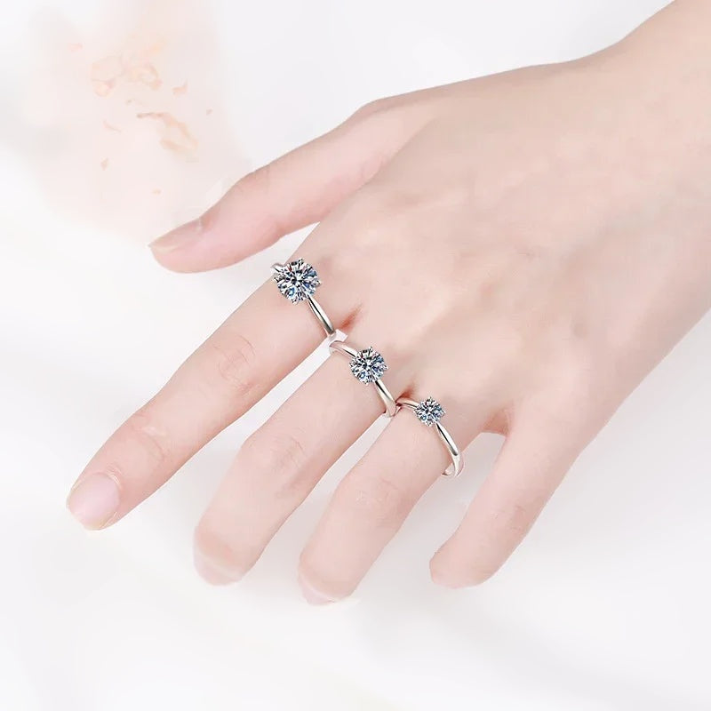 Mão com três anéis solitários de moissanite de tamanhos diferentes
