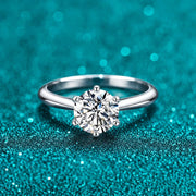 Anel Solitário de Moissanite Colorida com Aro Liso em prata 925 sobre fundo verde com brilho