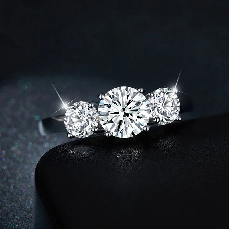 Anel três pedras de moissanite visto de frente em fundo escuro