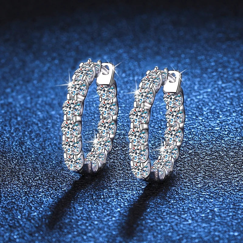 Par de argolas cravejadas de moissanite sobre fundo azul