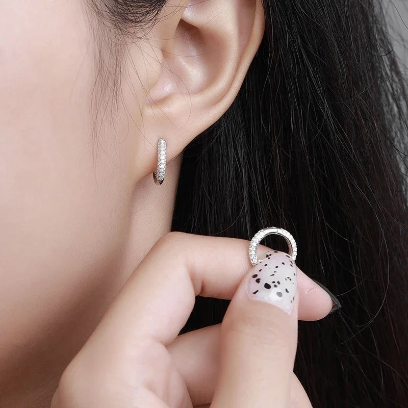 Mão segurando argolinha pavê de moissanite perto da orelha