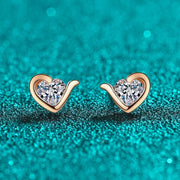 Par de brincos coração de moissanite em ouro rosé sobre fundo verde-água