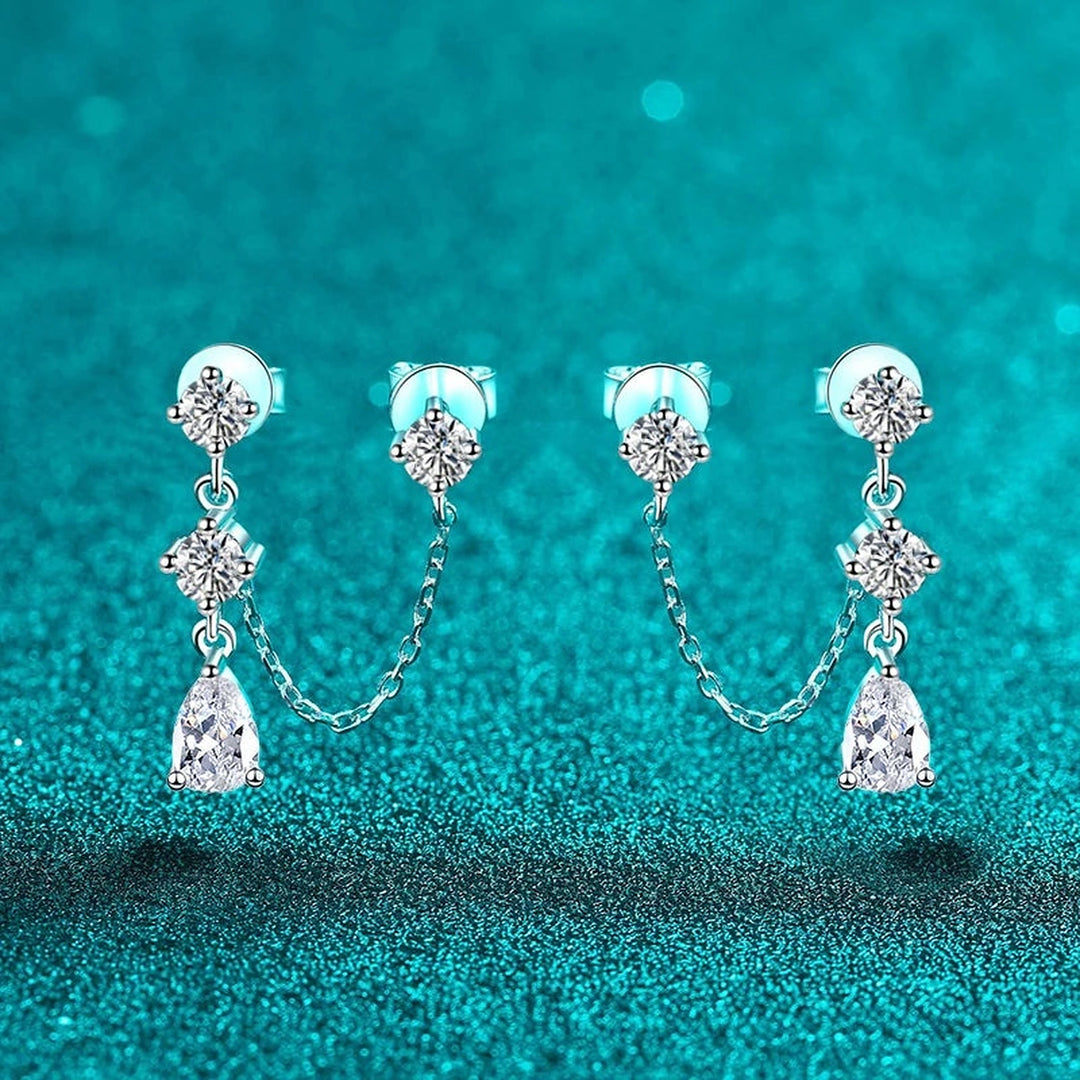 Par de brincos duplos com corrente e gota de moissanite sobre fundo verde-água