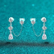 Par de brincos duplos com corrente e gota de moissanite sobre fundo verde-água