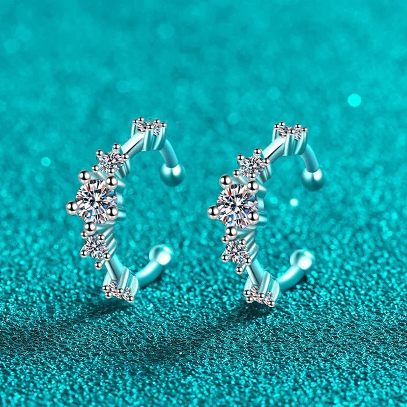 Par de ear cuffs de moissanite sobre fundo verde