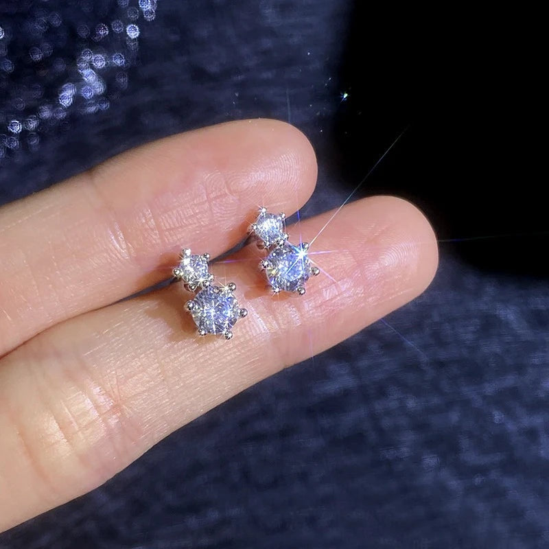 Brincos de duas moissanites apoiados nos dedos