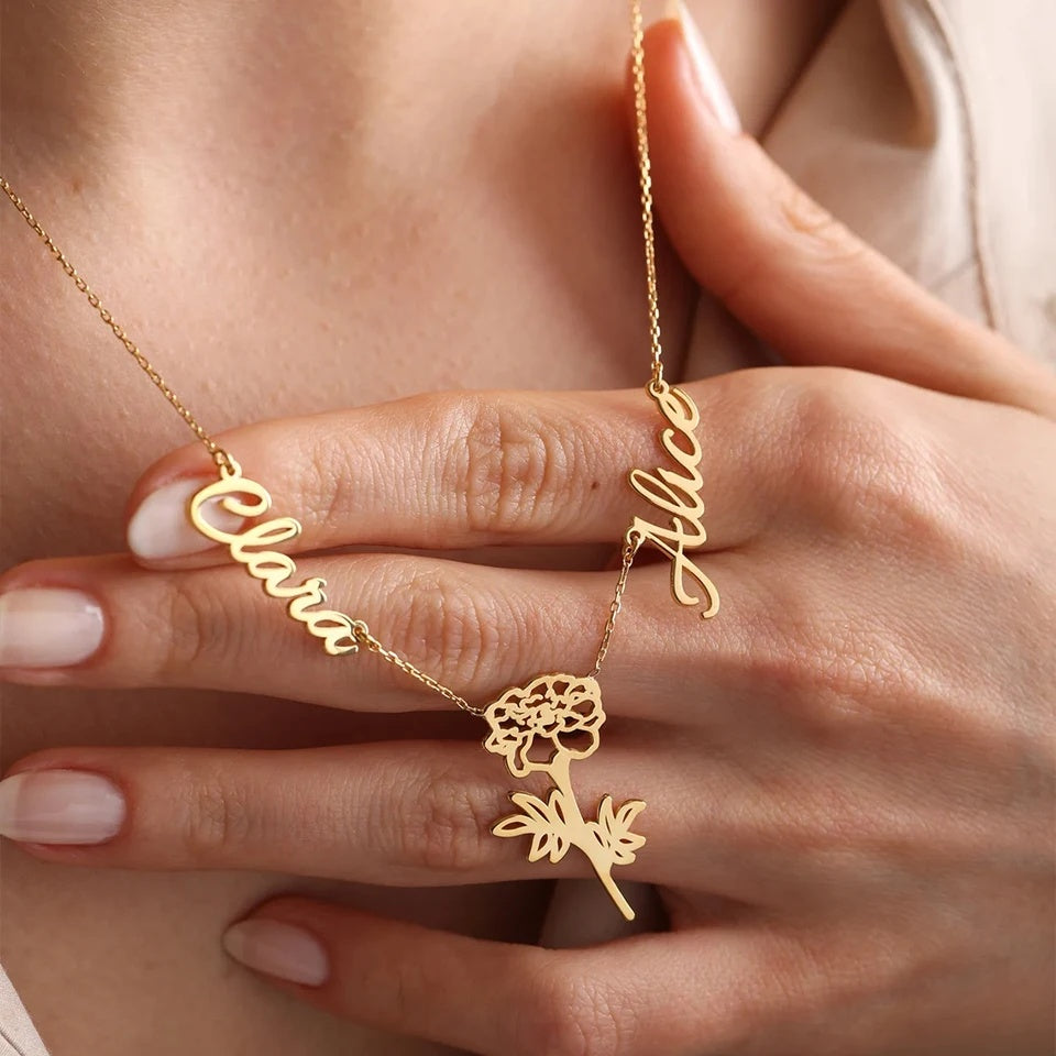Mão segurando o colar com 2 nomes e flor dourado