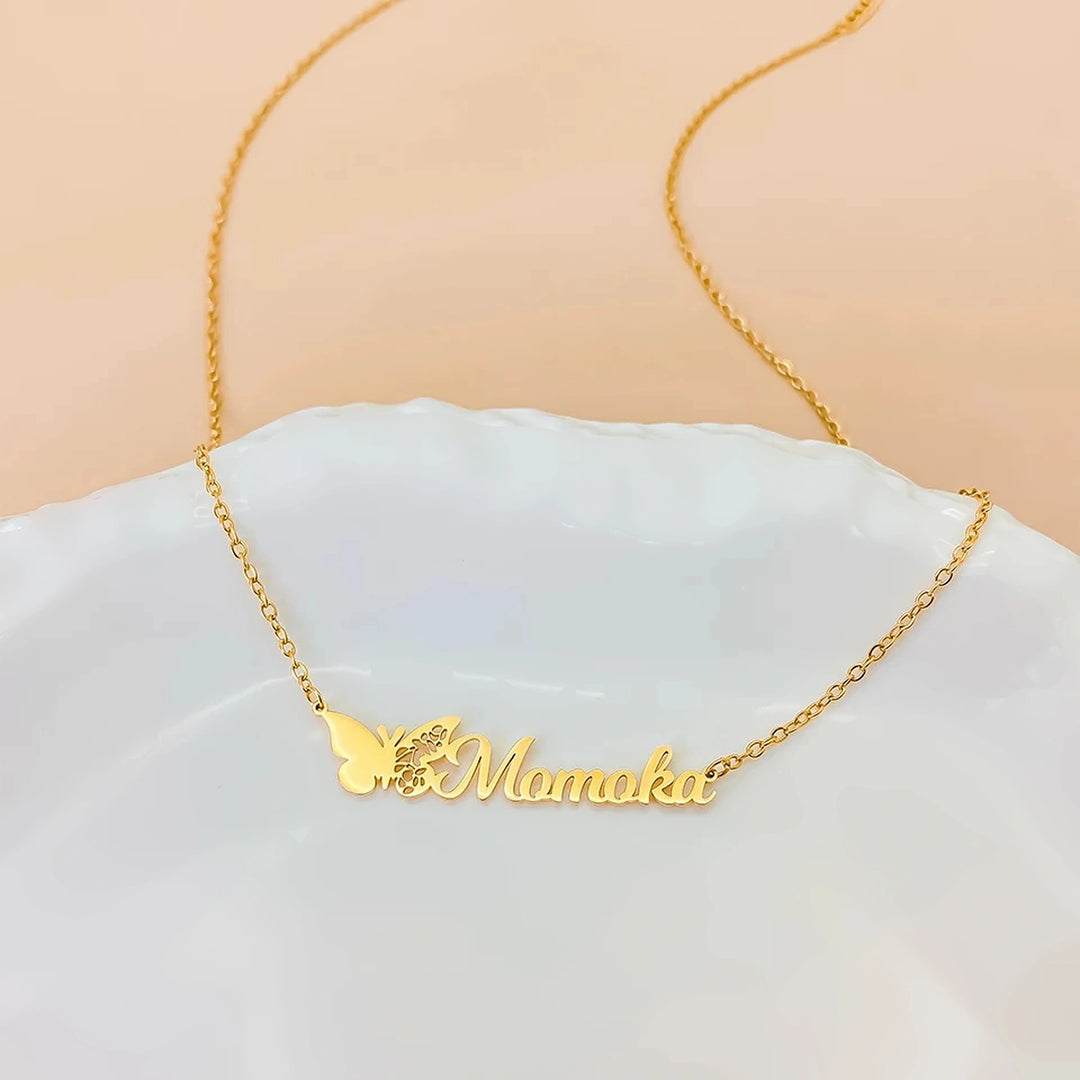 Colar com nome e borboleta do mês dourado Momoka sobre prato branco
