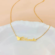 Colar com nome e borboleta do mês dourado Momoka sobre prato branco