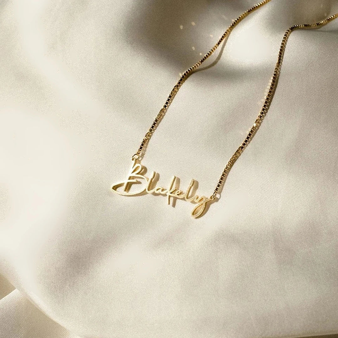 Colar com nome dourado em corrente veneziana sobre tecido claro
