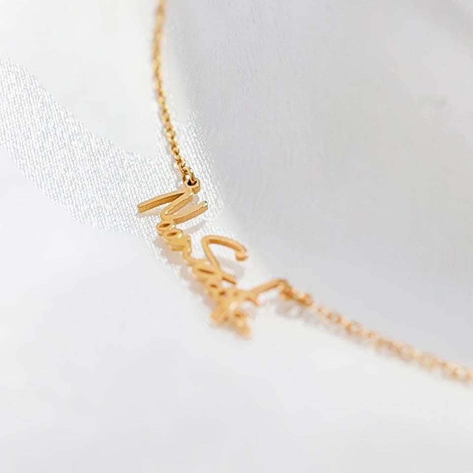 Detalhe do nome em letra cursiva do colar dourado