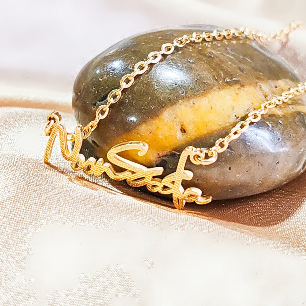 Colar com nome dourado apoiado em pedra