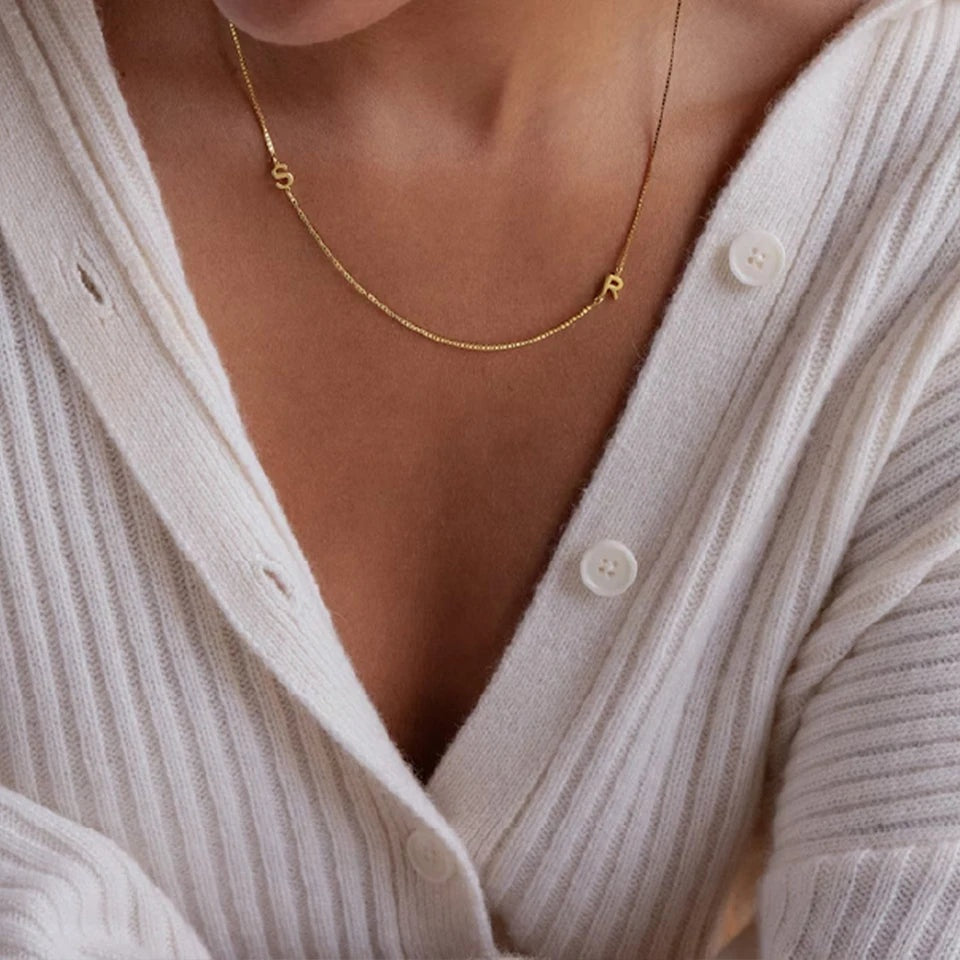 Colar dourado com iniciais assimétricas no colo