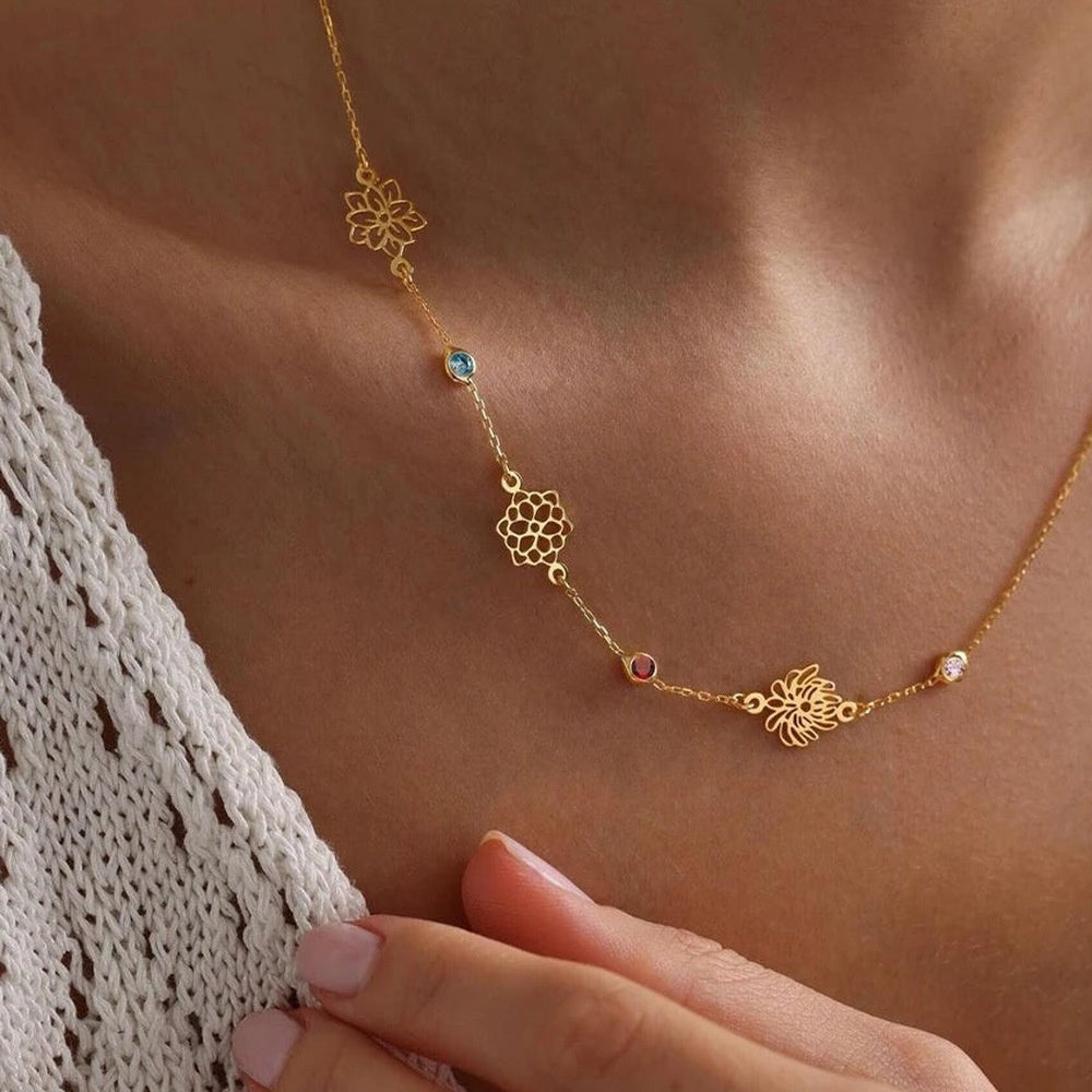 Colar flor do mês dourado com quatro flores e pedras usado no colo