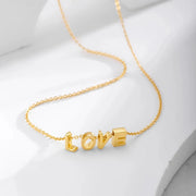 Colar com iniciais dourado com letras passantes formando LOVE