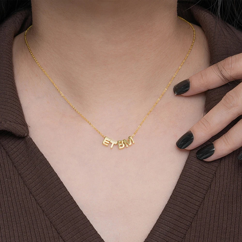Colar com iniciais dourado de quatro letras usado com blusa marrom