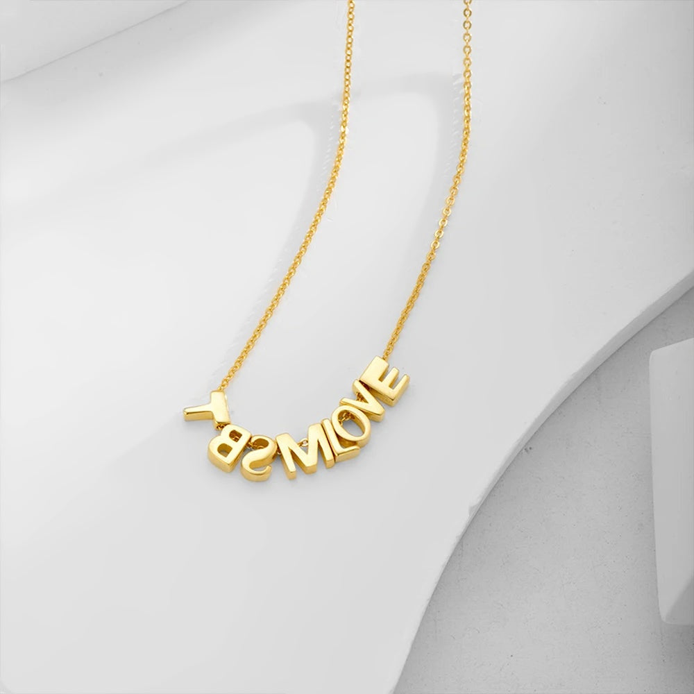 Colar com iniciais e coração dourado de sete letras sobre fundo branco