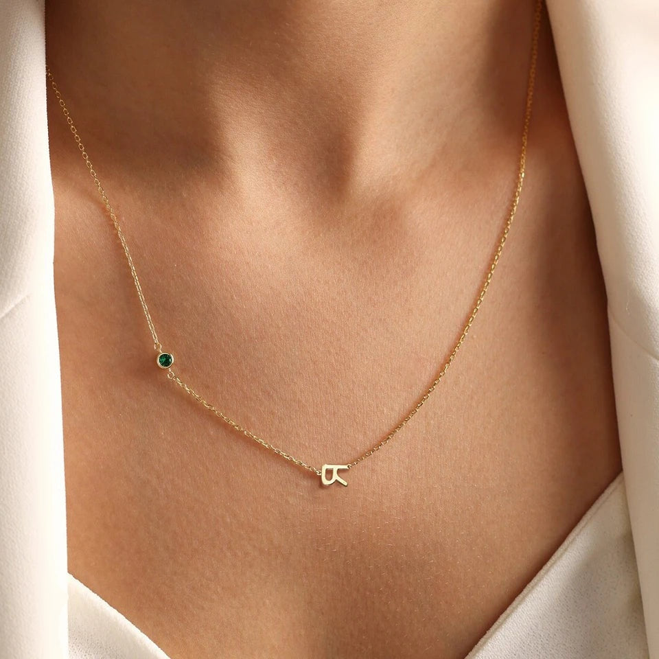 Colar delicado com uma inicial e pedra verde no pescoço