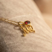 Colar com inicial cursiva M dourado com pedra do mês vermelha