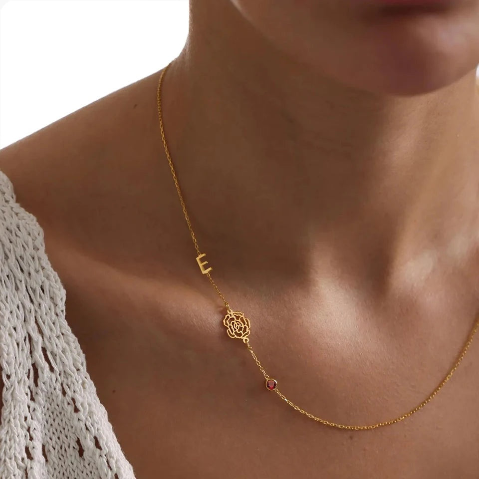Colar dourado com inicial e flor do mês assimétrico no pescoço