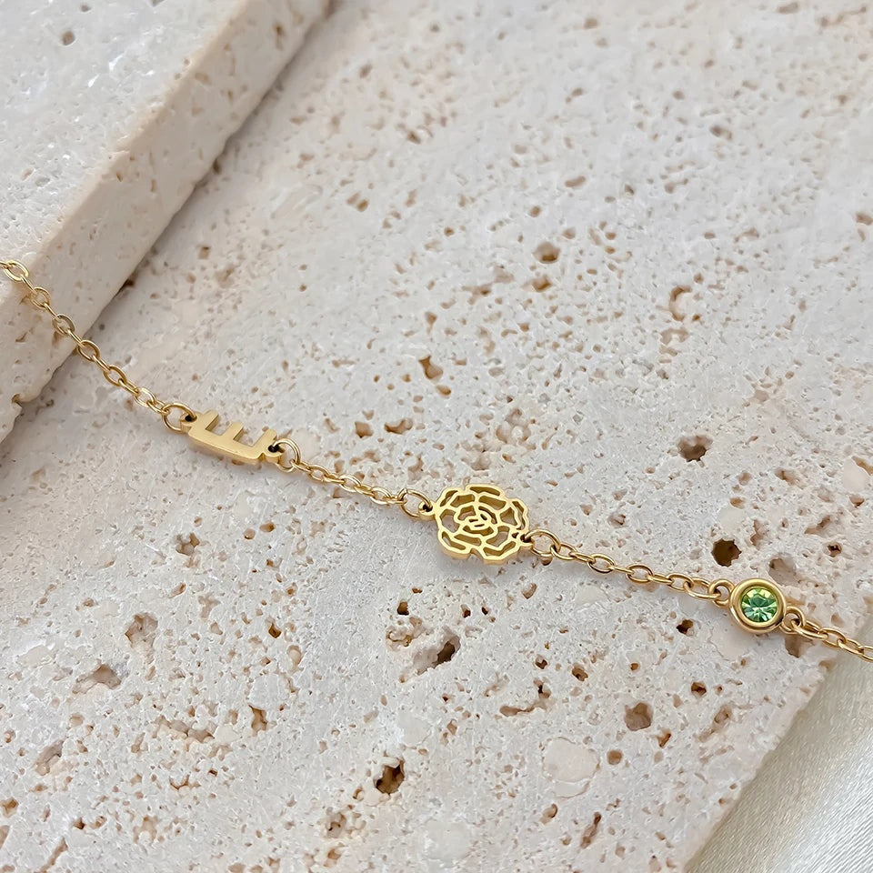 Detalhe da inicial, da flor vazada e da pedra verde do colar