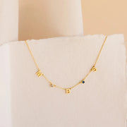 Colar com letras M B S e pedras do mês dourado sobre papel