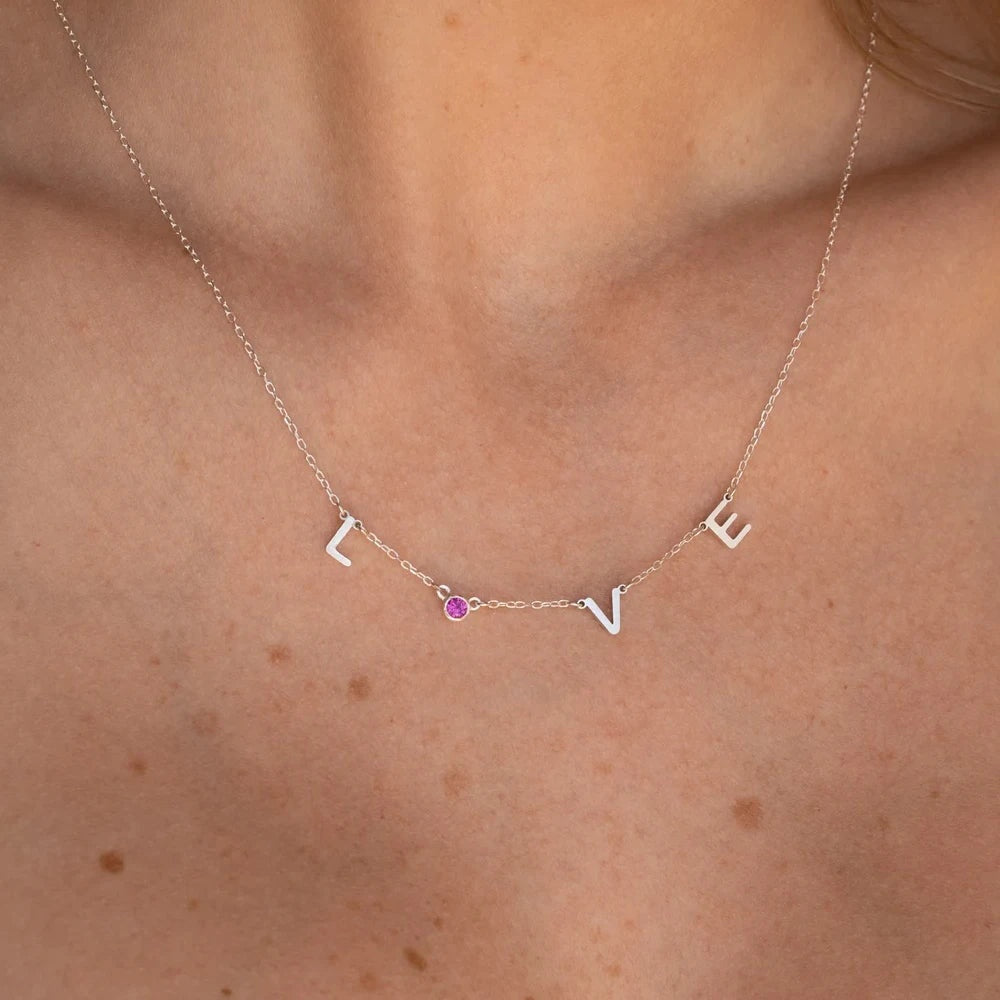 Colar LOVE com letras espaçadas e pedra rosa prata no pescoço