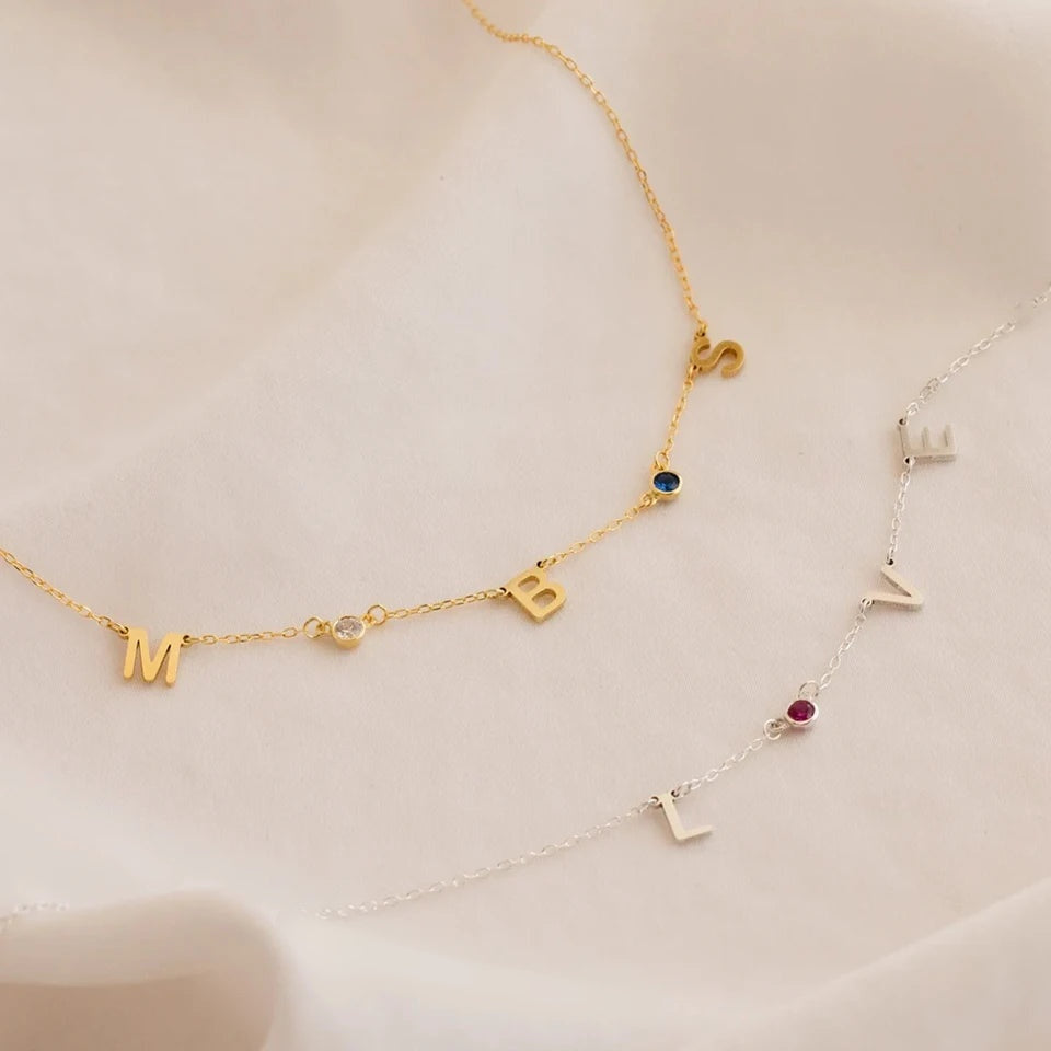 Colares com letras espaçadas e pedras do mês dourado e prata