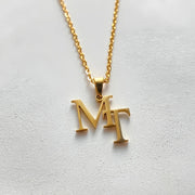Colar monograma com iniciais M e T entrelaçadas dourado
