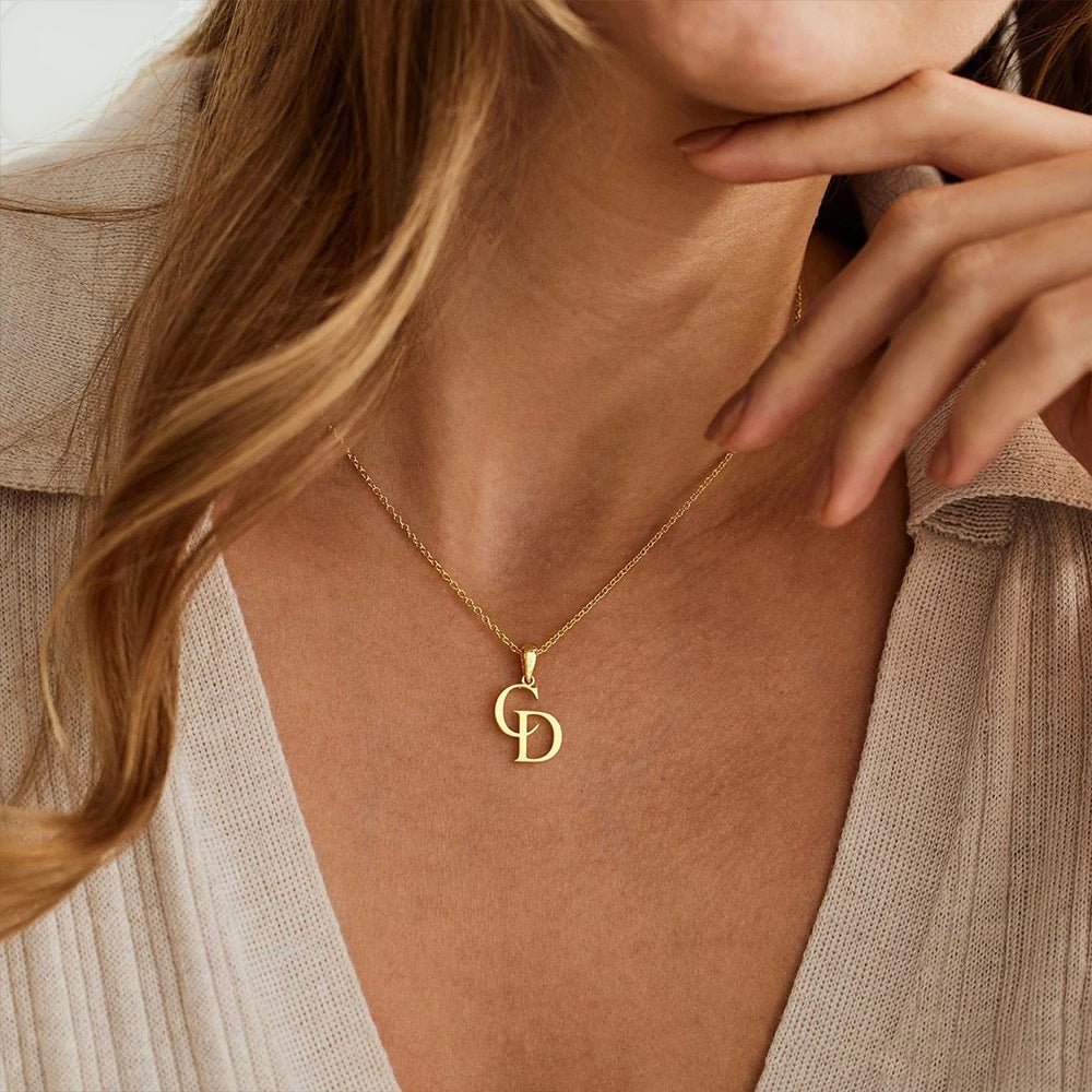 Colar com duas iniciais entrelaçadas dourado com cardigã bege