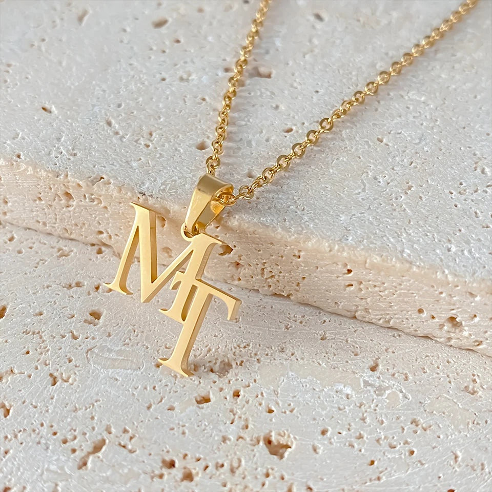 Detalhe das letras entrelaçadas do colar monograma dourado