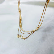 Colar com nome duplo dourado com corrente fita sobre tecido branco