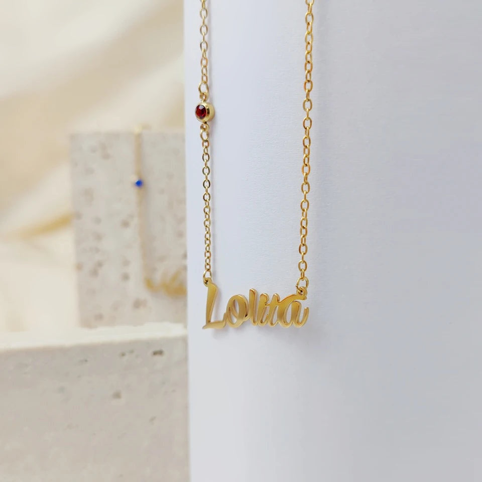 Colar com nome dourado e pedra vermelha pendurado
