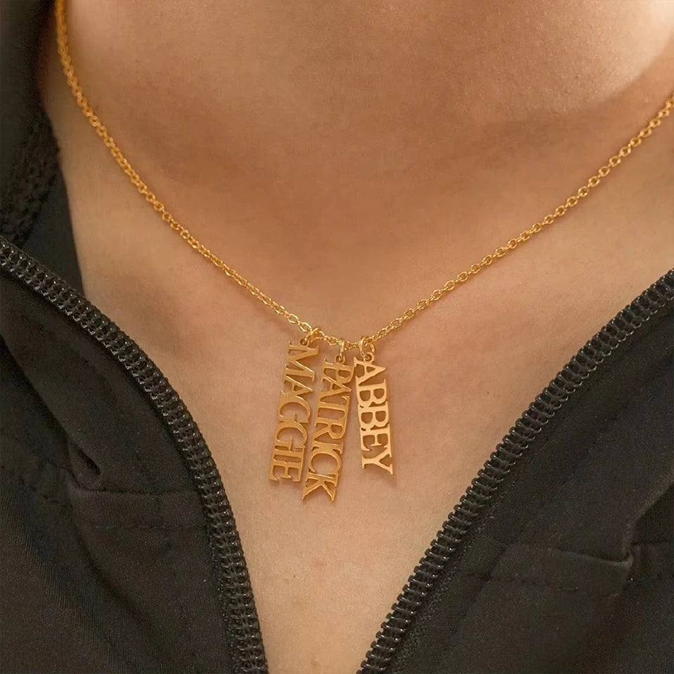 Colar de nomes verticais dourado usado com blusa escura