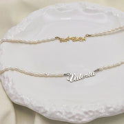 Colares de pérolas de água doce com nome dourado e prata sobre prato branco