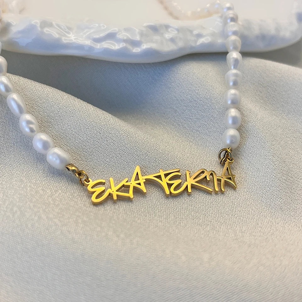 Colar de pérolas com nome em letra de forma dourado visto de perto