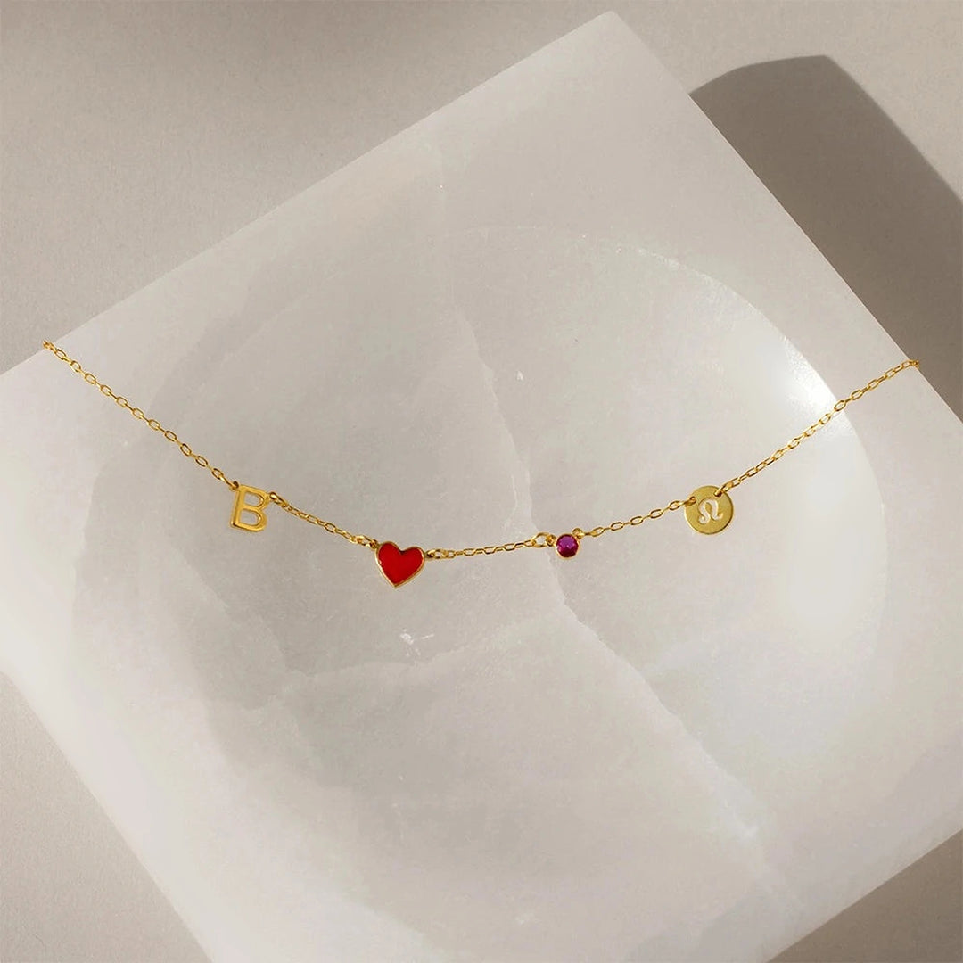 Colar de signo dourado com inicial, coração vermelho e pedra do mês