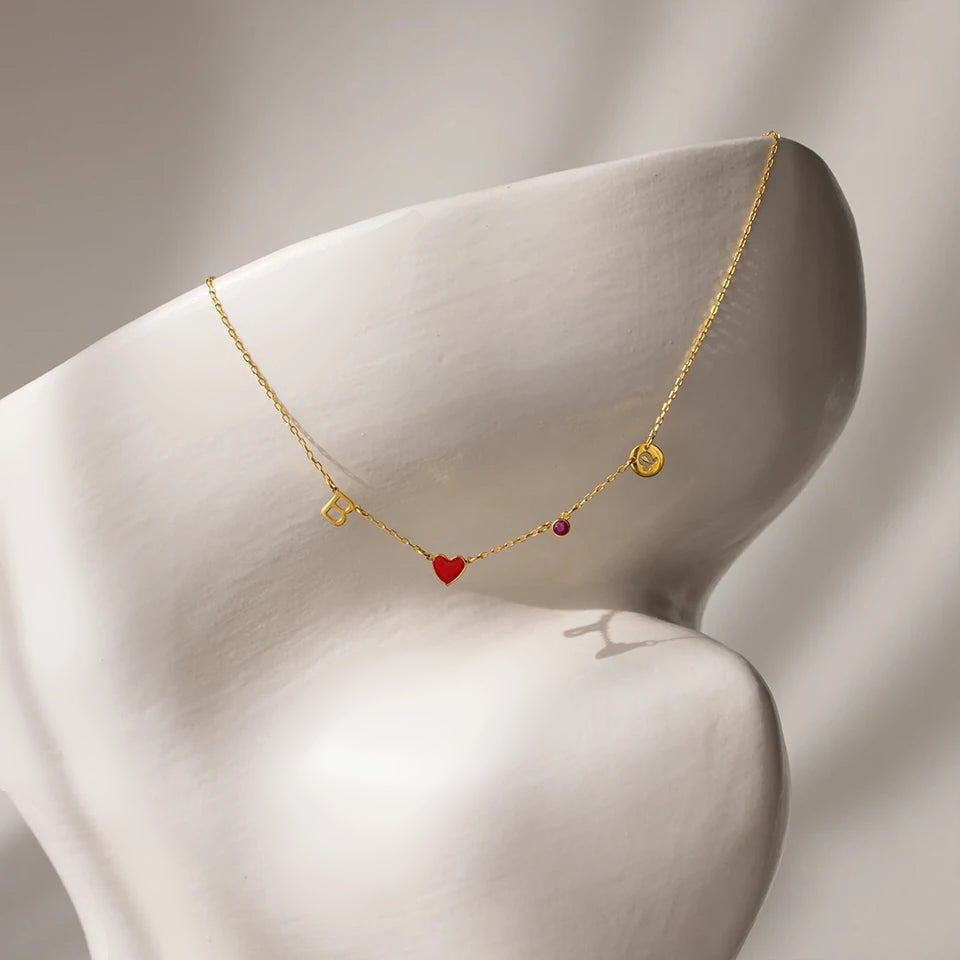 Colar com coração esmaltado vermelho e signo dourado sobre peça branca