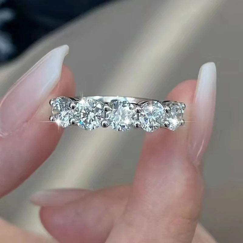 Meia aliança 5 pedras de moissanite segurada entre os dedos