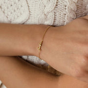 Pulseira com nome dourada no pulso com suéter branco