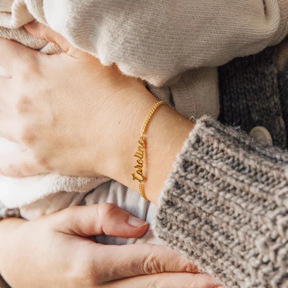 Pulseira groumet dourada com nome Caroline usada com suéter