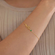 Pulseira flor do mês dourada com pedra verde de maio no pulso
